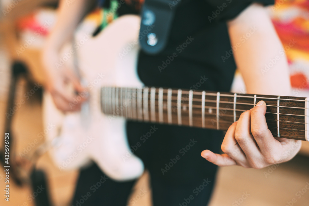 teenager playing electric guitar at home