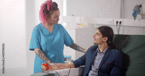 Nurse instructing man donor in reclining chair in hospital