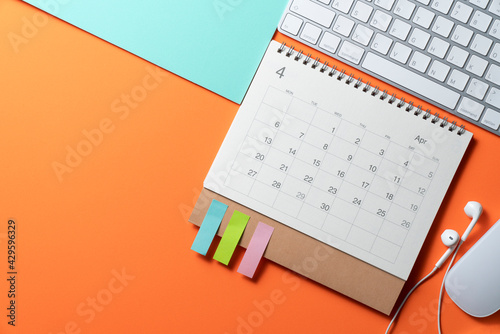 close up of calendar and keyboard on the table with orange and green background, planning for business meeting or travel planning concept