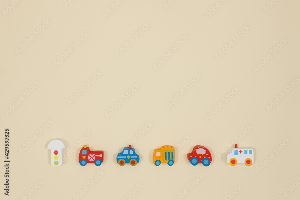Wooden toys of traffic light, civil servants cars and touring car. Yellow background.