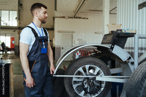 Mechanic balancing  car wheel on balancer in workshop