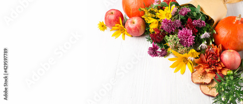 Autumn composition with flowers, leaves, pumpkins on white wooden background.