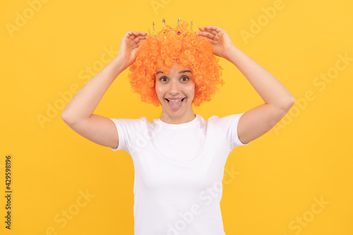 happy egoistic funny girl with fancy look wearing orange hair wig and princess crown, winner