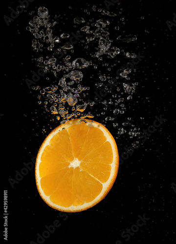 Orange slice falling in water
