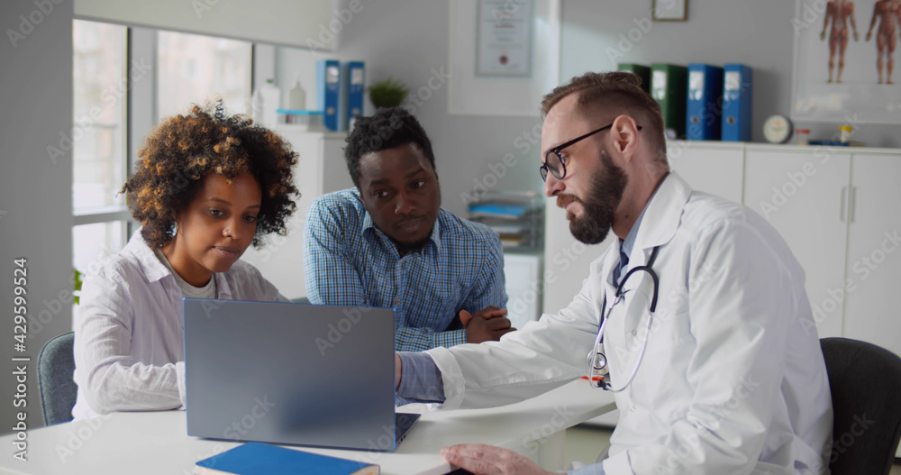 African couple looking at ultrasound baby image on screen of laptop at doctor office African couple looking at ultrasound baby image on screen of laptop at doctor office
