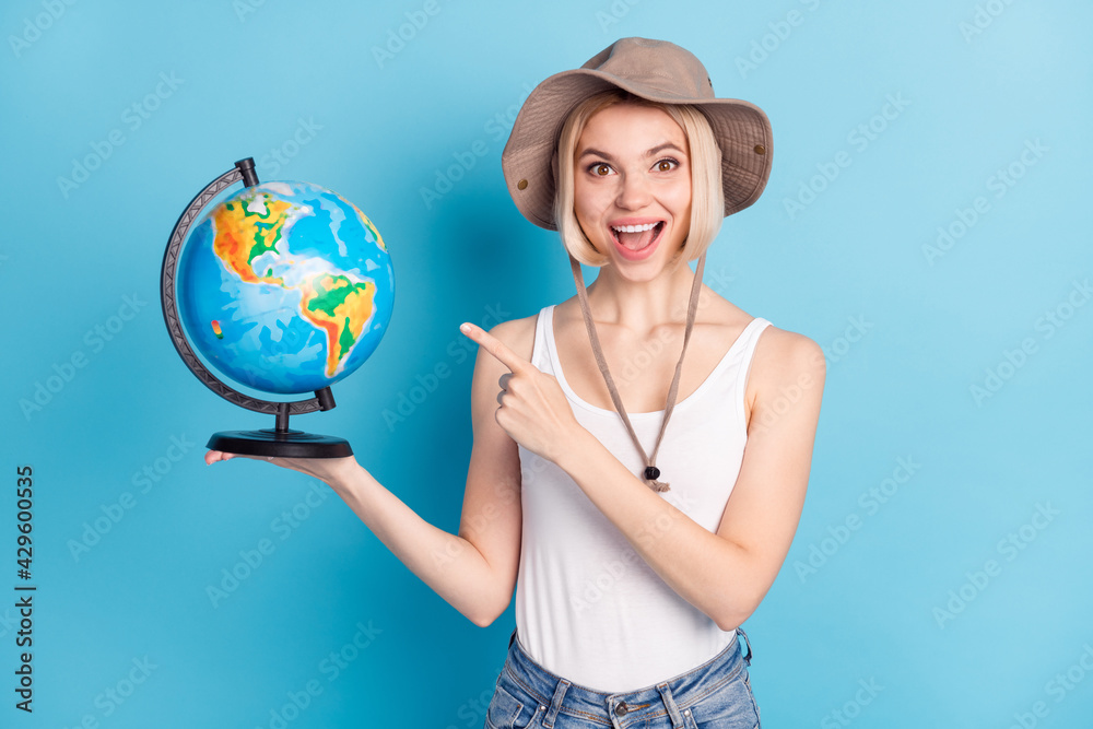 Fototapeta premium Portrait of funny astonished lady open mouth indicate finger hand hold globe isolated on blue color background