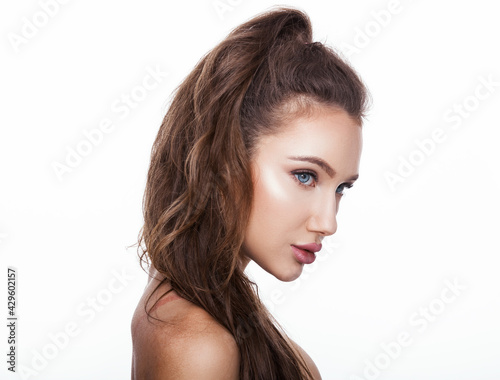 Beautiful face of young adult woman with clean fresh skin. Beauty portrait of brunette with blue eyes standing on white background copy space