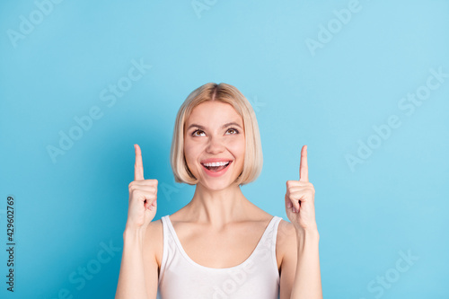 Portrait of pretty positive lady look indicate fingers up empty space isolated on blue color background