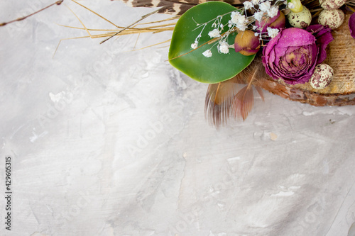 Easter composition with eggs, feathers and flowers on grey background