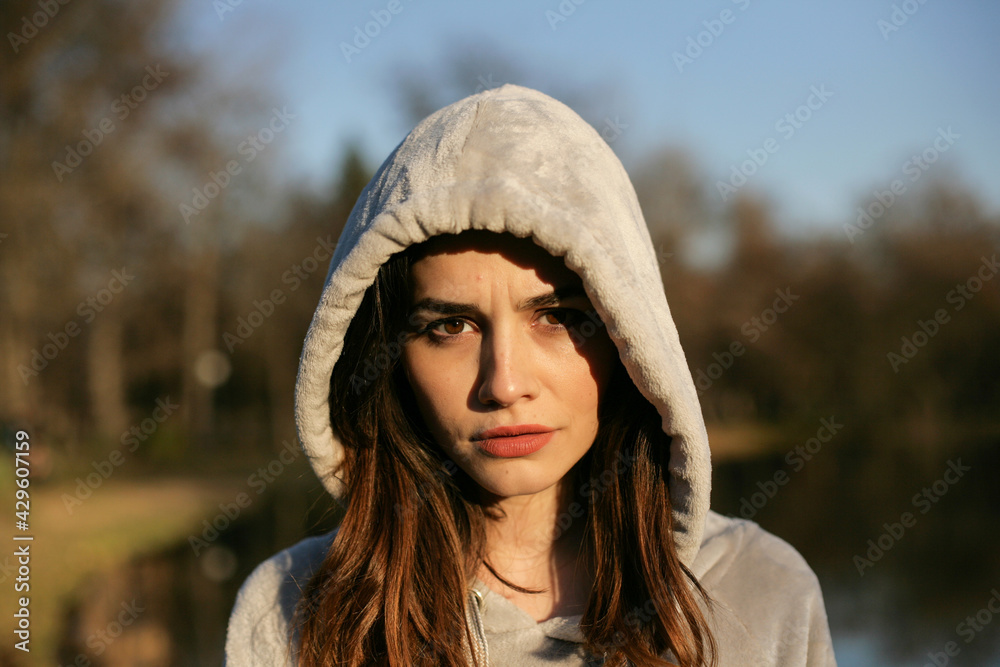 Portrait of a serious young woman with hood in nature. Portrait of a serious young woman with hood in nature.