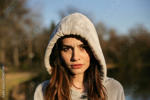 Portrait of a serious young woman with hood in nature.