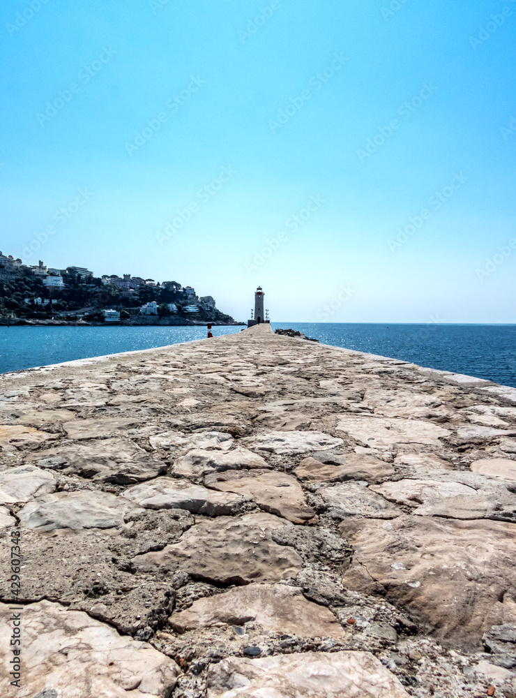 Fototapeta premium Jetée en pierre menant au phare du port Lympia à Nice sur la Côte d'Azur