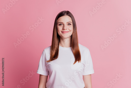 Young smiling cheerful girl look at camera wear white t-shirt on pink wall