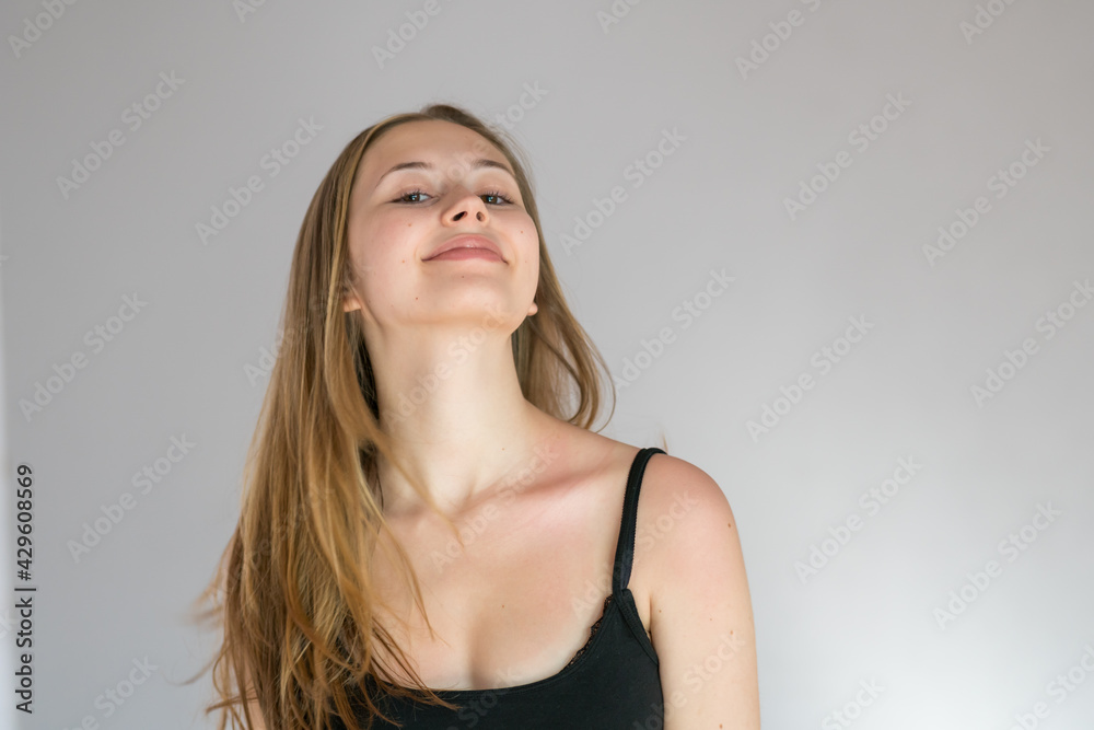 Studio portrait of a young blonde woman smiling showing her neck Studio portrait of a young blonde woman smiling showing her neck