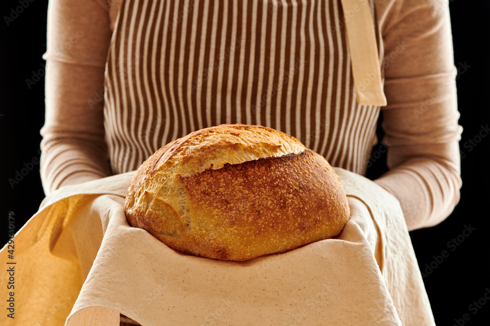 Baker holding loaf of homemade bread