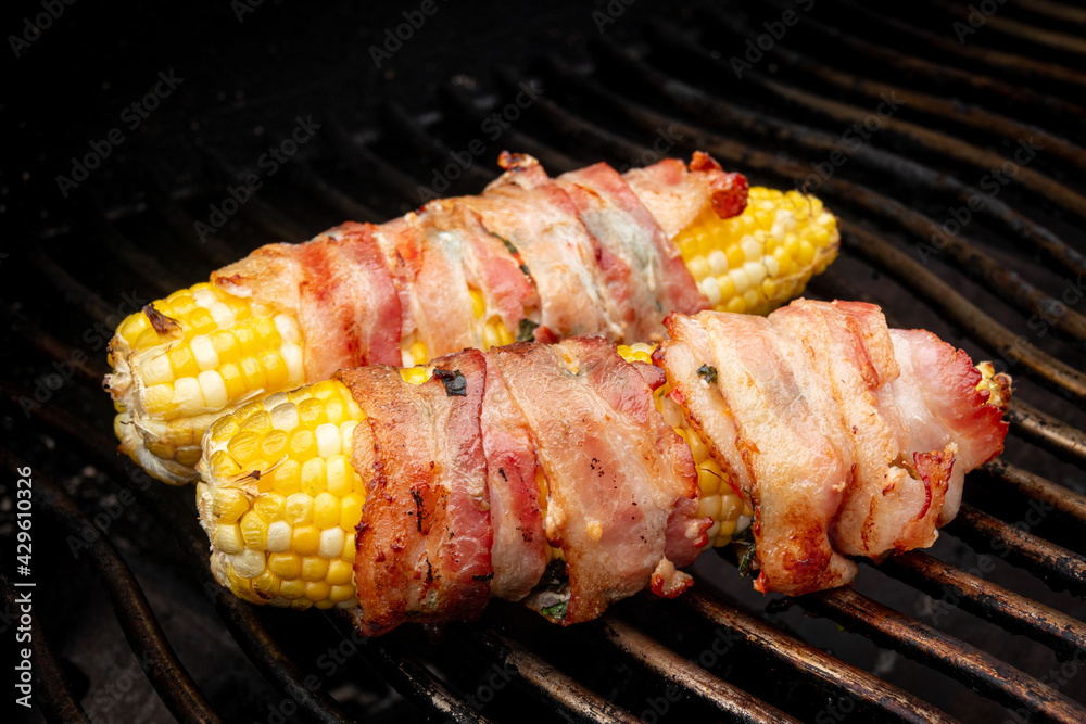 corn on the cob wrapped in bacon over the bbq grill corn on the cob wrapped in bacon over the bbq grill