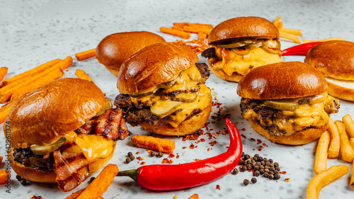 Foto A closeup shot of tasty smash burgers, French fries, and red spicy peppers on th