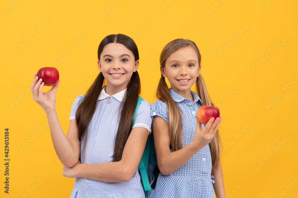 Happy primary school children hold tasty apples fruit yellow background, school snack Happy primary school children hold tasty apples fruit yellow background, school snack