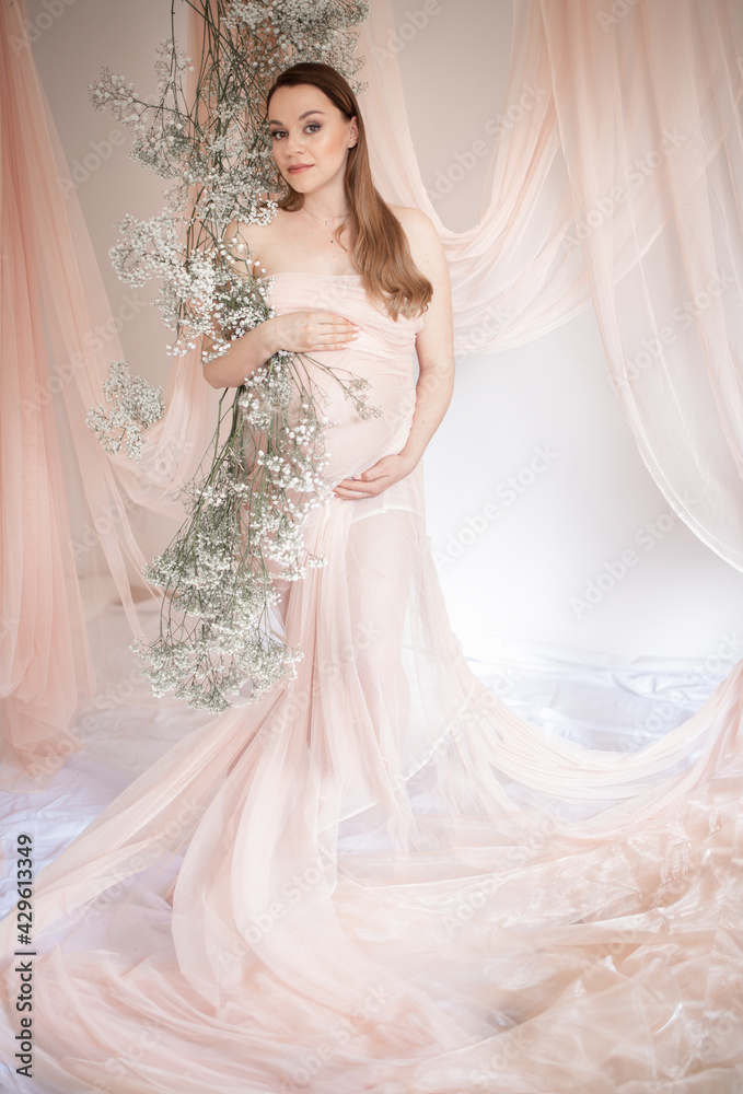 Beautiful and happy pregnant woman in floral decoration. Pregnancy. Happy mother. Future mother.
