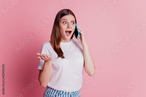 Photo of excited girl use smartphone talk friends open mouth look side on pink wall