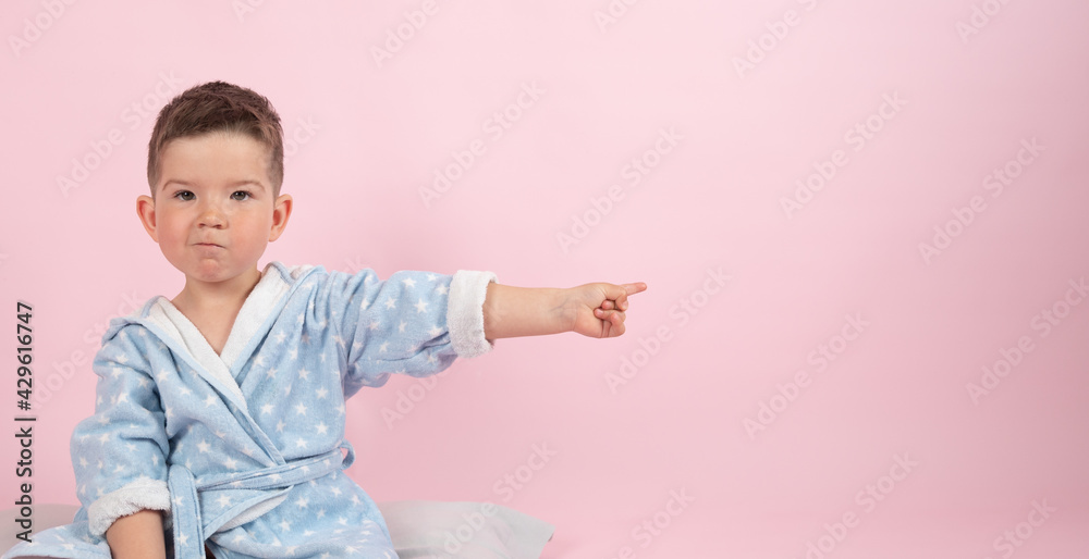 Cute boy on pink background points with his hand to the side, photo for advertising product Cute boy on pink background points with his hand to the side, photo for advertising product