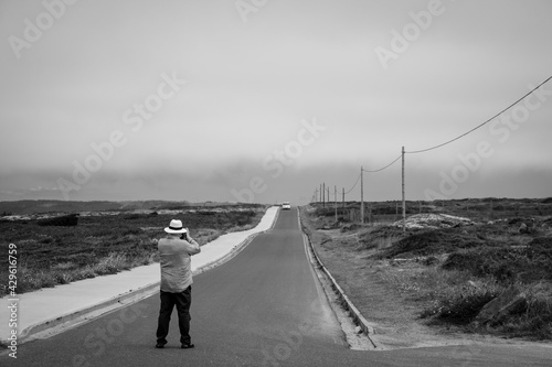 CORRUBEDO, SPAIN - JULY 27, 2020: A man takes a photo of the road that leads to the Corrubedo lighthouse, at the cape of the same name in Galicia (Spain) photo