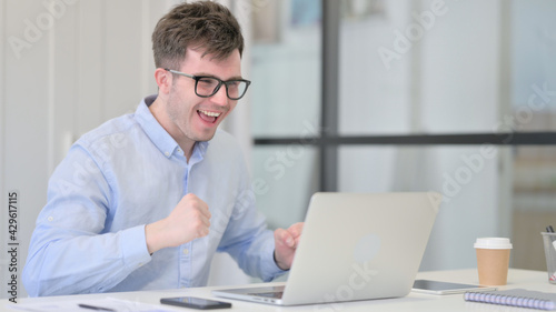 Successful Young Man Celebrating on Laptop at Work 