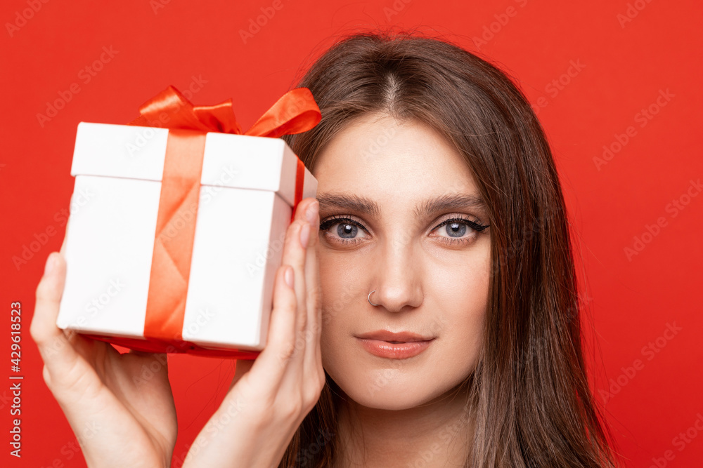 Portrait of a young woman with a gift box on a red background Portrait of a young woman with a gift box on a red background