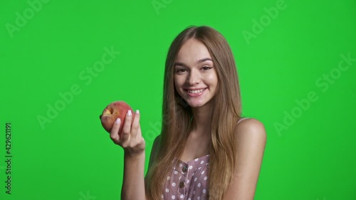 Smiling girl wearing summer dress smiling and holding a peach