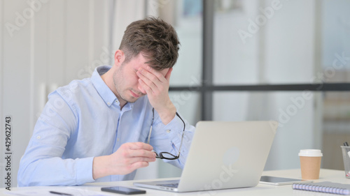 Young Man with Laptop having Headache 