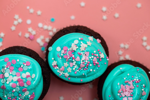 Sweet party food. Cupcakes with turquoise icing and sugar sprinkles in the form of pink hearts and stars. Top view