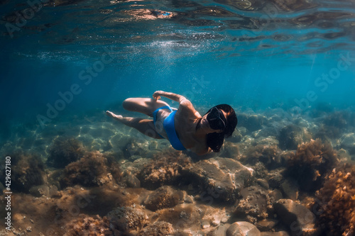 Woman freediver posing underwater in transparent ocean