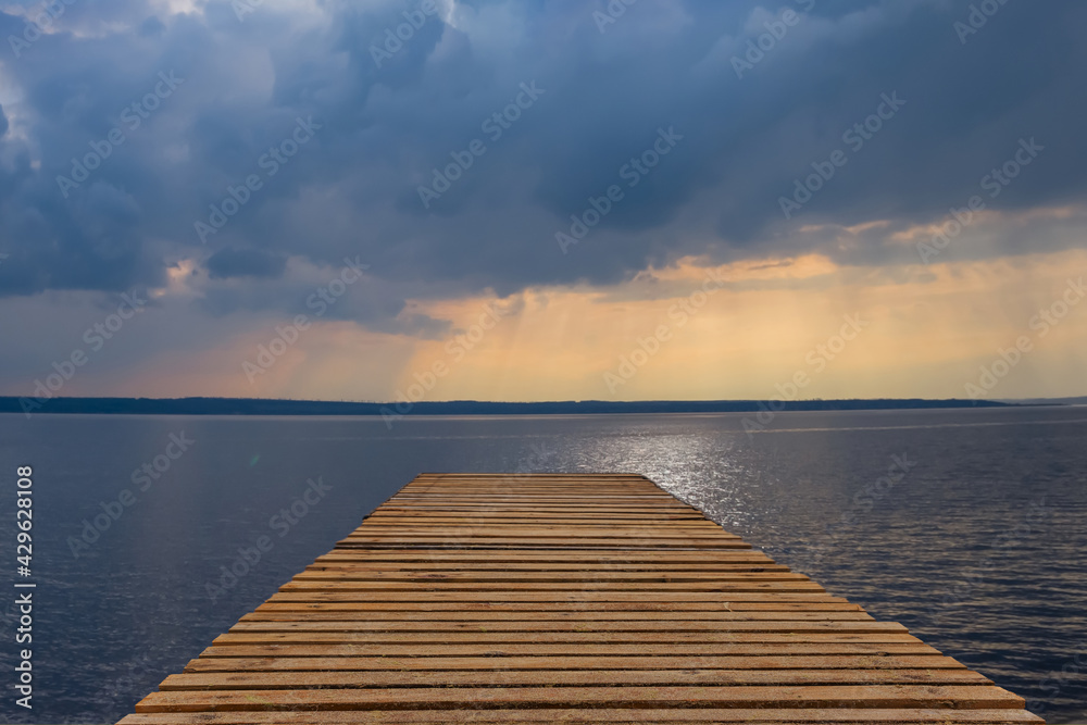 wooden pier on sea coast under dramatic cloudy sky