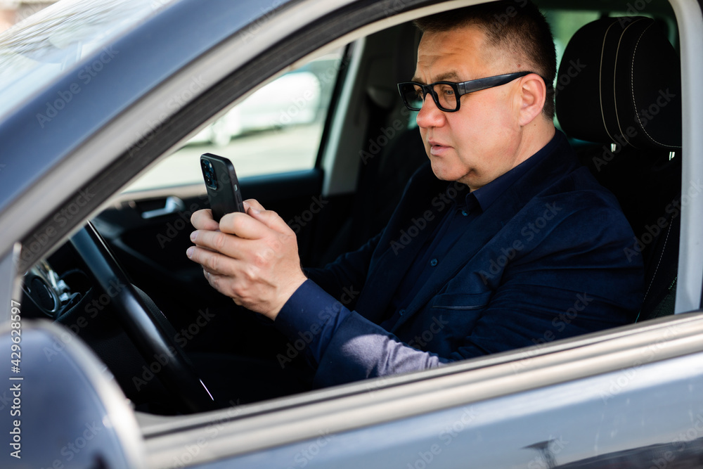 Middle age reckless man using his smartphone behind the wheel