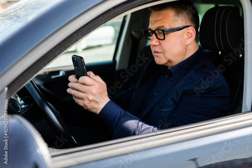Middle age reckless man using his smartphone behind the wheel