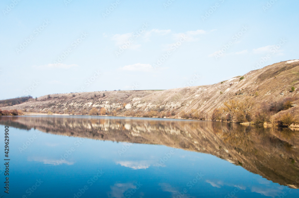 a large body of water under the mountain. wide river with a steep bank. deep blue pond. beautiful calm lake