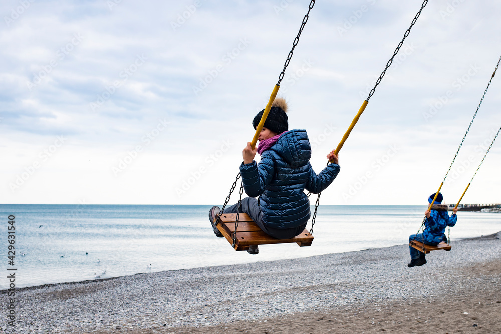 Happy little girl swinging on a swing overlooking the sea and sky.