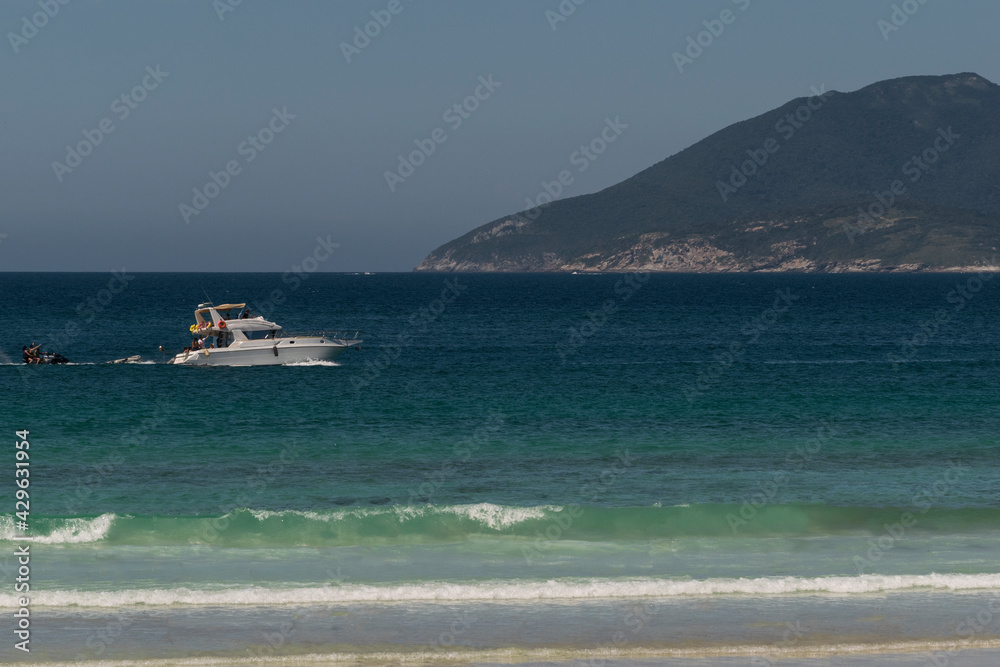 praia com montanhas, iates, rochas e lindas ondas