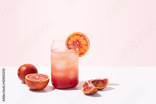 Summer bloody orange lemonade in a glass, healthy functional water on a pink background. photo