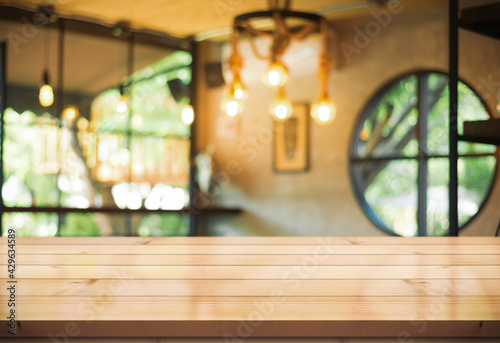 Empty wooden table top with lights bokeh on blur restaurant background.