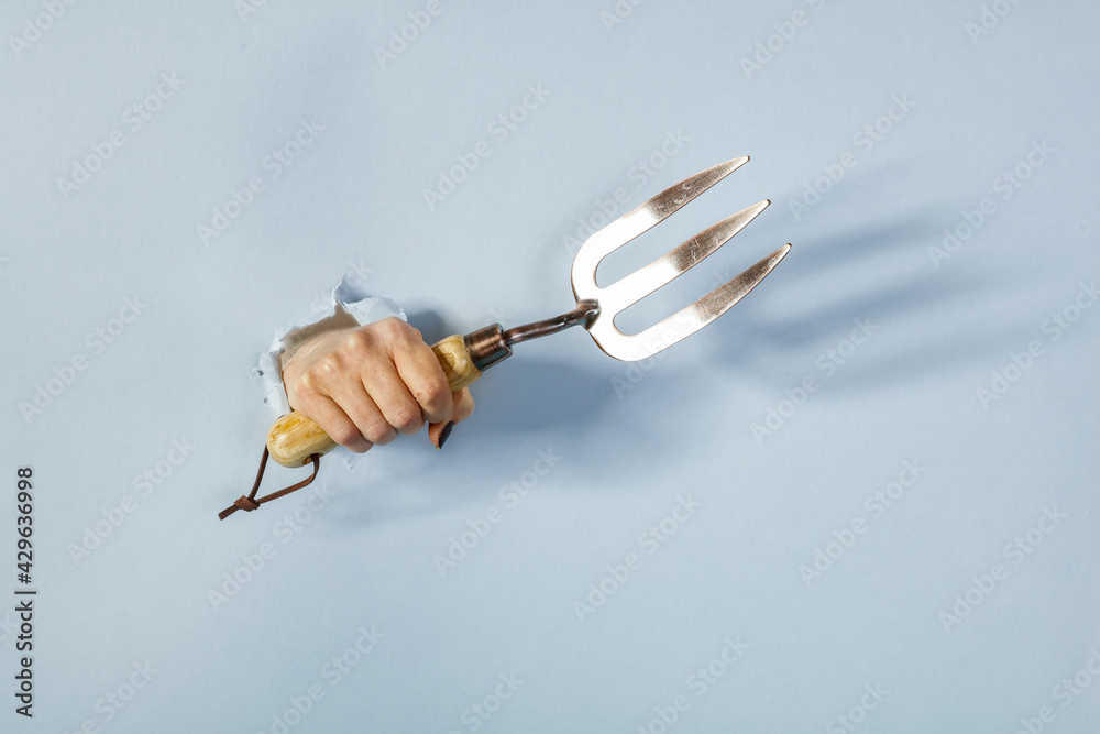 Hole in the paper, hand holds a product on a gray background, banner Hole in the paper, hand holds a product on a gray background, banner