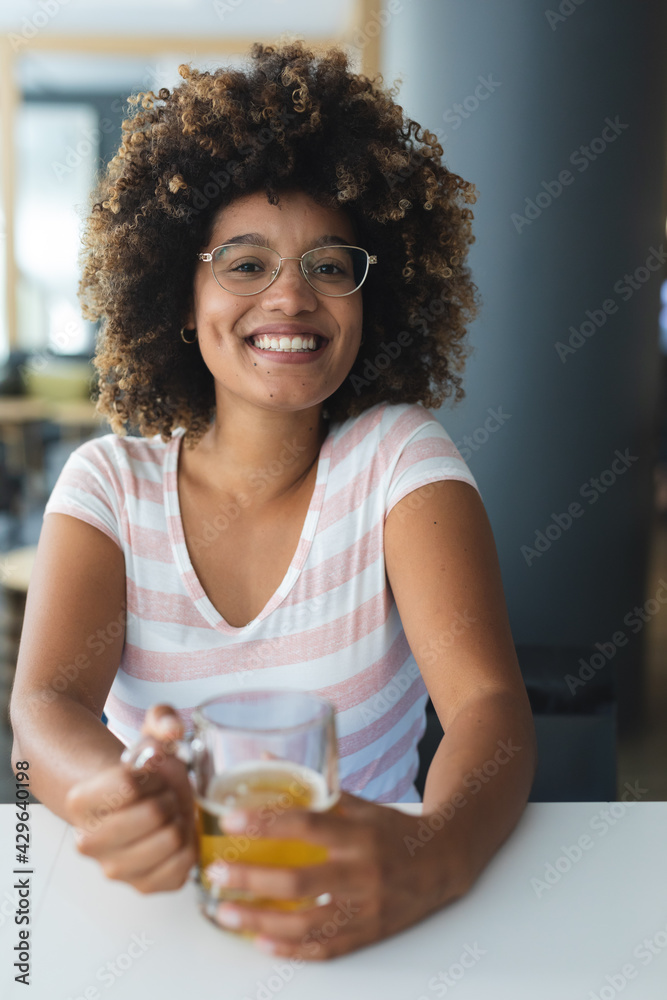 Portrait of mixed race woman sitting at table smiling having beer Portrait of mixed race woman sitting at table smiling having beer