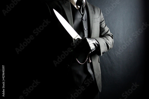 Portrait of Man in Dark Suit and Leather Gloves Holding Sharp Knife. Well Dressed Mafia Hit Man. Gentleman Assassin.