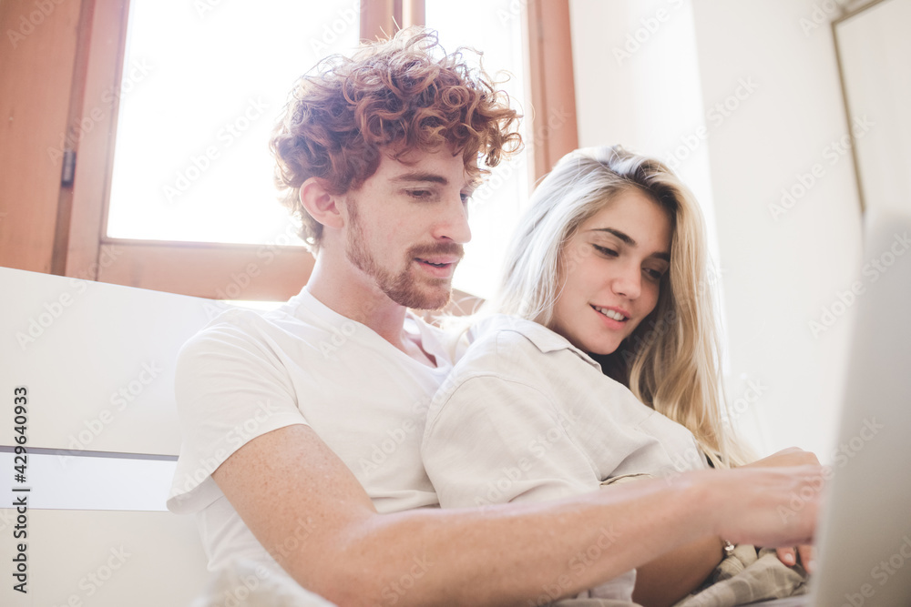 Young couple in love using computer indoor Young couple in love using computer indoor