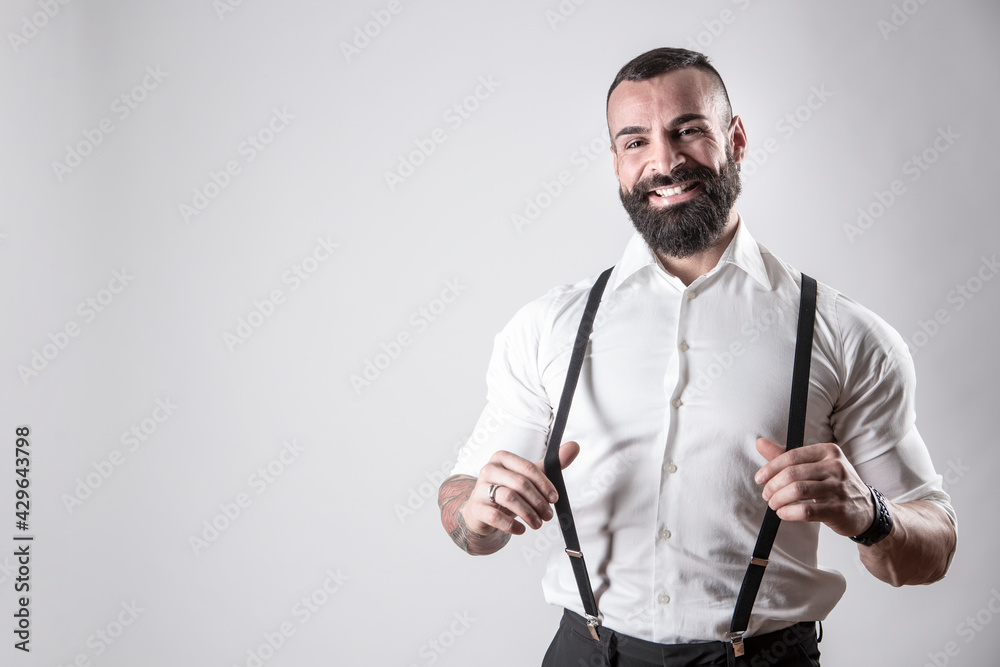 Uomo moro con la barba con camicia bianca tiene le bretelle nere con  espressione divertita, isolato su sfondo Stock-Foto | Adobe Stock