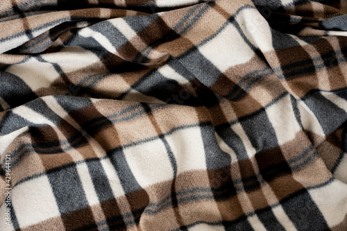 Wrinkled black and brown checkered clothing background. Fabric with a pattern of black white brown cells.