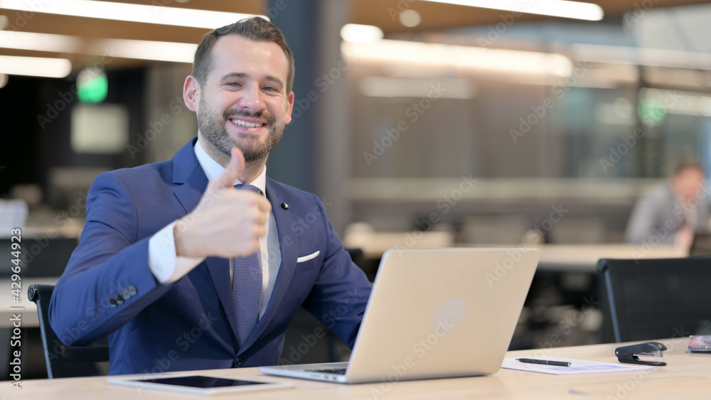 Thumbs Up by Middle Aged Businessman with Laptop at Work 