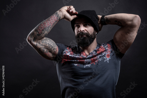Uomo moro muscoloso con maglietta color fantasia si mette apposto il cappellino , isolato su sfondo nero
 photo