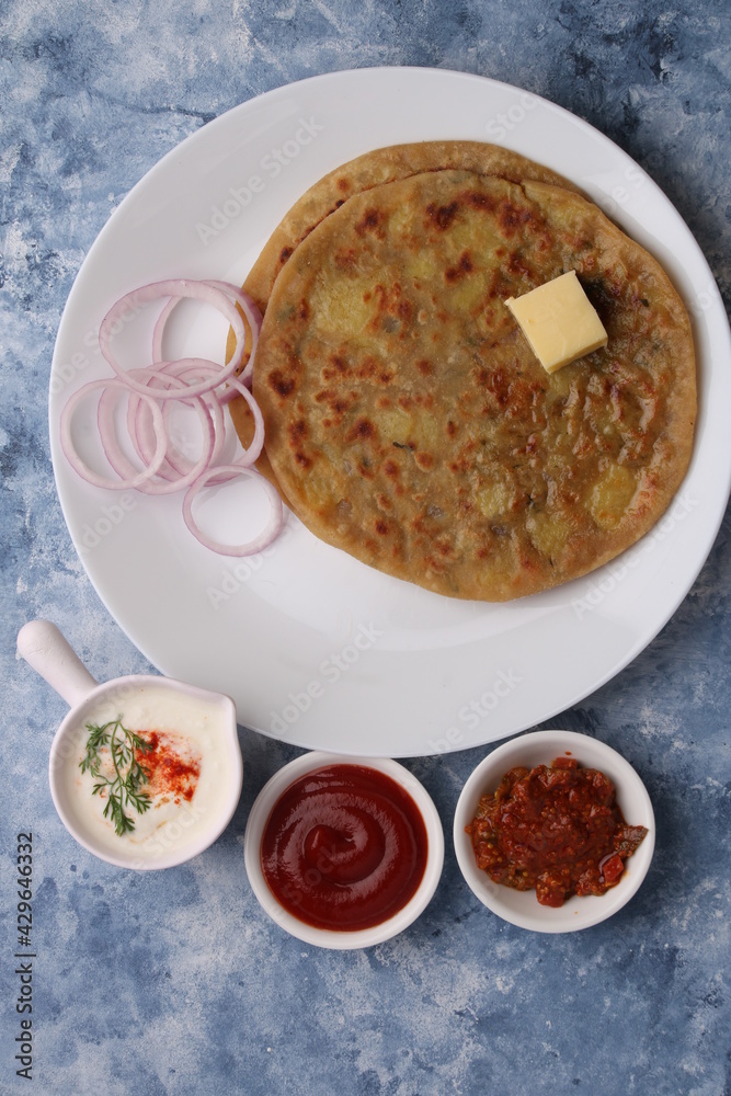 Traditional Indian food Aloo paratha or potato stuffed flat bread. served with pickle tomato ketchup and curd, butter, onion. Traditional Indian food Aloo paratha or potato stuffed flat bread. served with pickle tomato ketchup and curd, butter, onion.