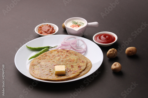 Traditional Indian food Aloo paratha or potato stuffed flat bread. served with pickle tomato ketchup and curd, butter, onion, chili.
